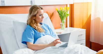 Woman using laptop in hospital bed