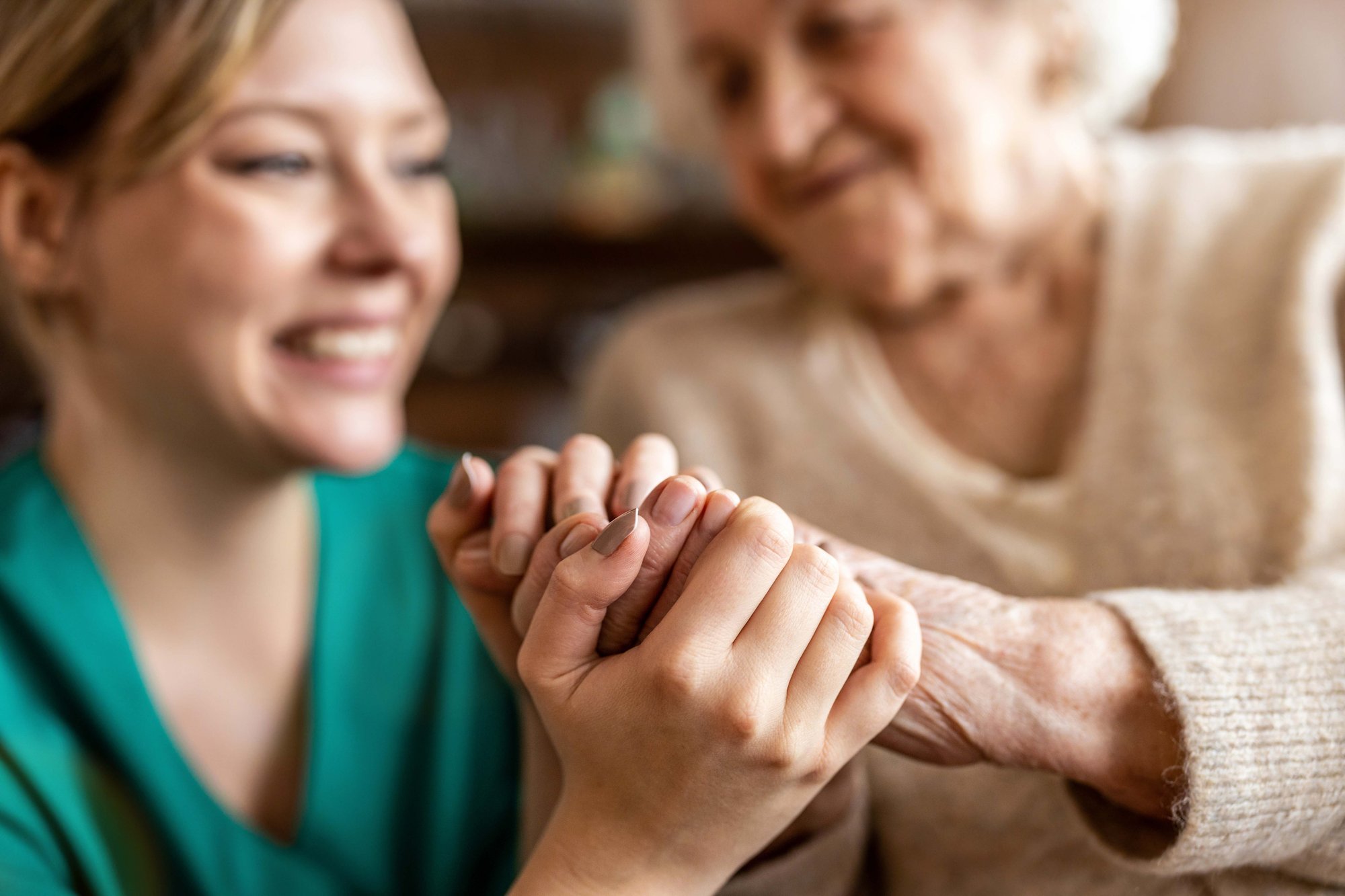 nurse holding hand of elderly woman