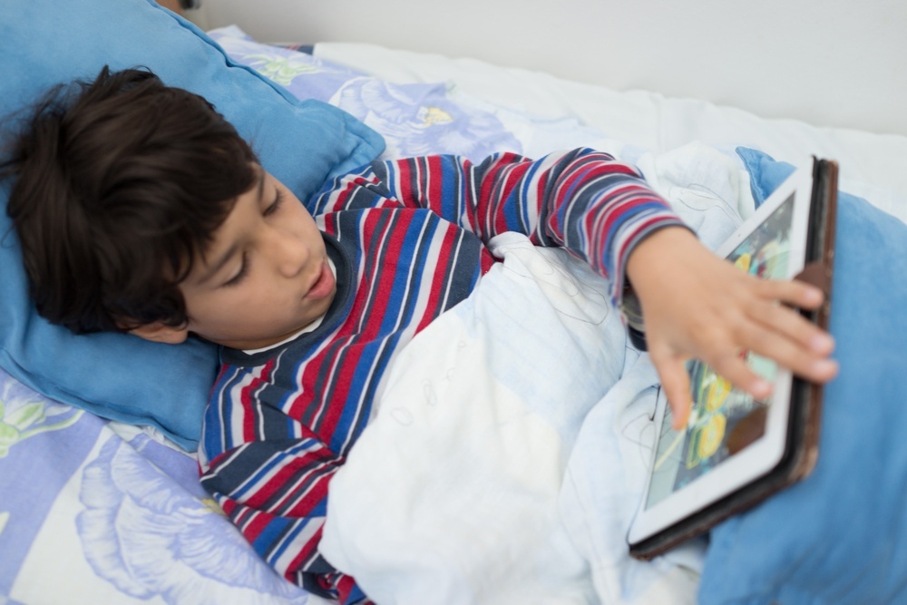 Child patient in hospital bed using tablet