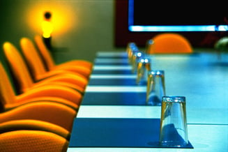 Orange chairs sat in a line up against a blue conference table. 